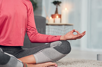 Buy stock photo Cropped shot of an unrecognizable woman sitting cross legged and meditating in her living room while at home