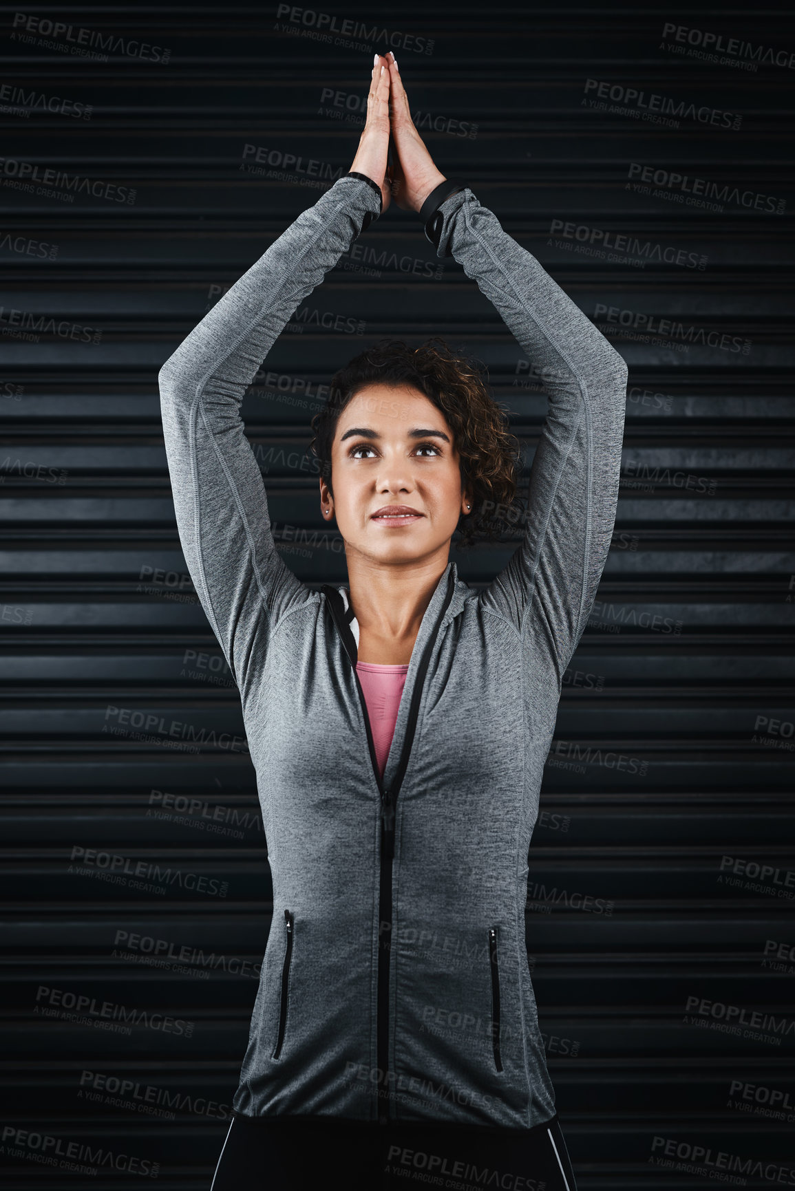 Buy stock photo Cropped shot of a young attractive woman standing against a black background with her arms raised in a yoga position