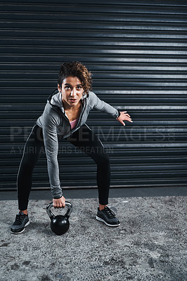 Buy stock photo Full length shot of an attractive young woman exercising against a black background and lifting kettle bells