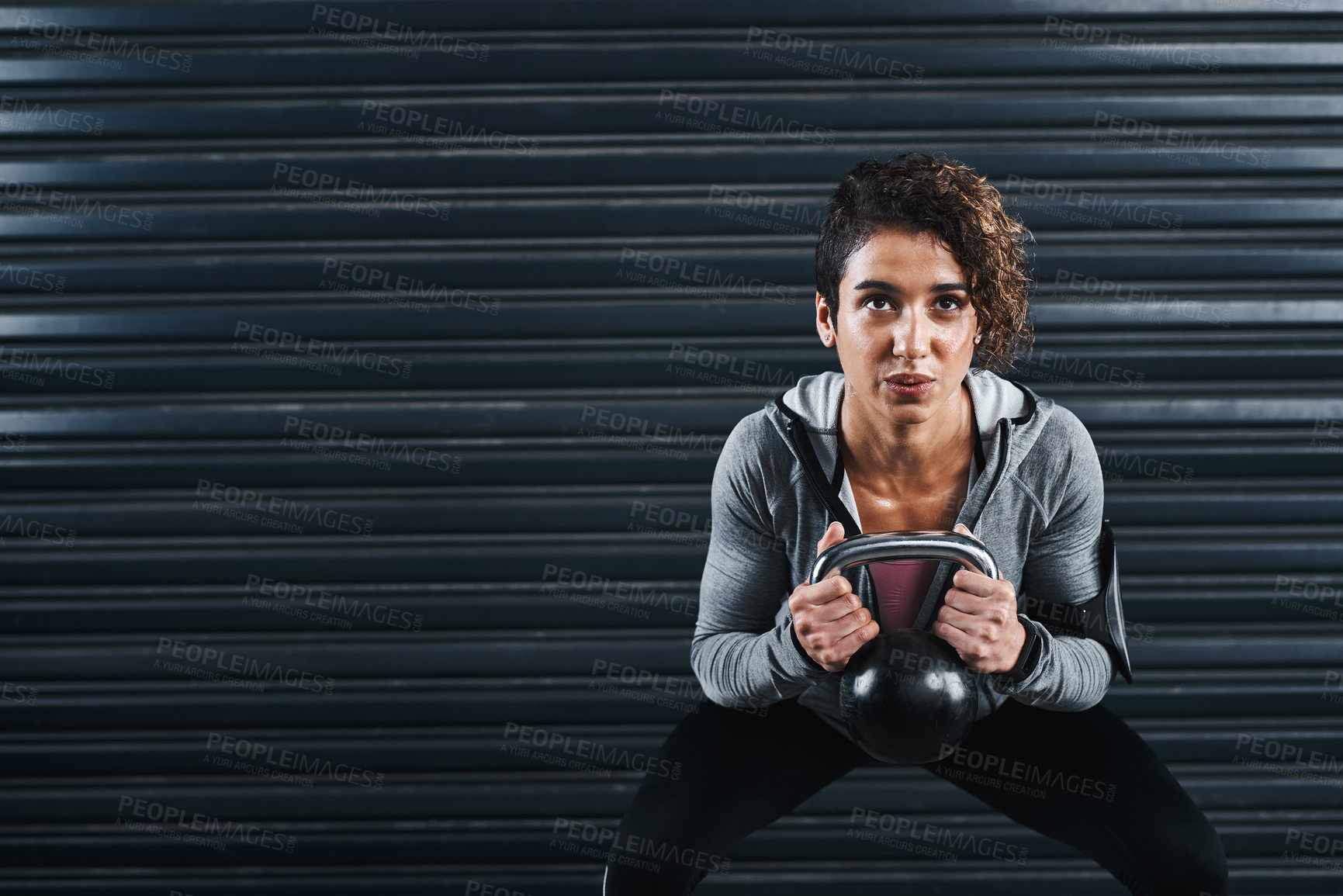 Buy stock photo Full length shot of an attractive young woman exercising against a black background and lifting kettle bells