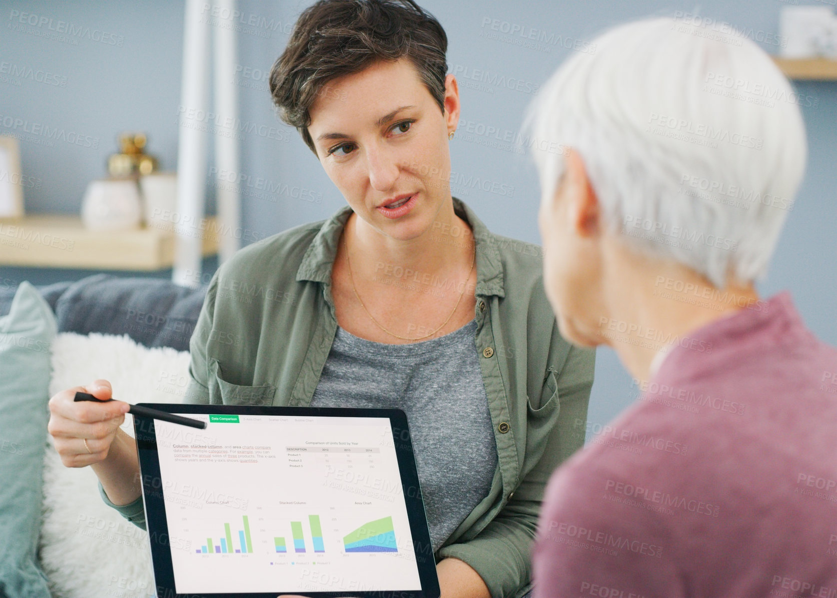 Buy stock photo Cropped shot of an attractive young woman showing a senior patient her medical results on a tablet while sitting down