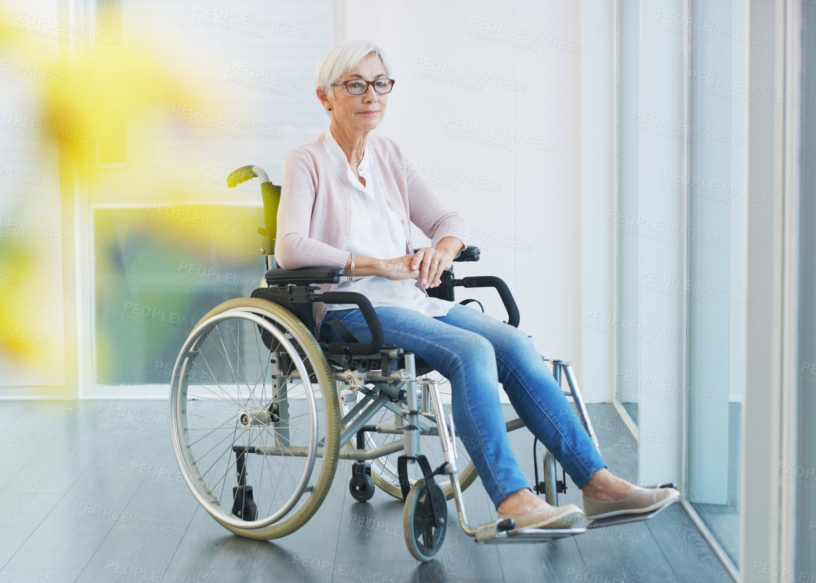 Buy stock photo Full length shot of a contemplative senior woman sitting in a wheelchair while looking away in a nursing home