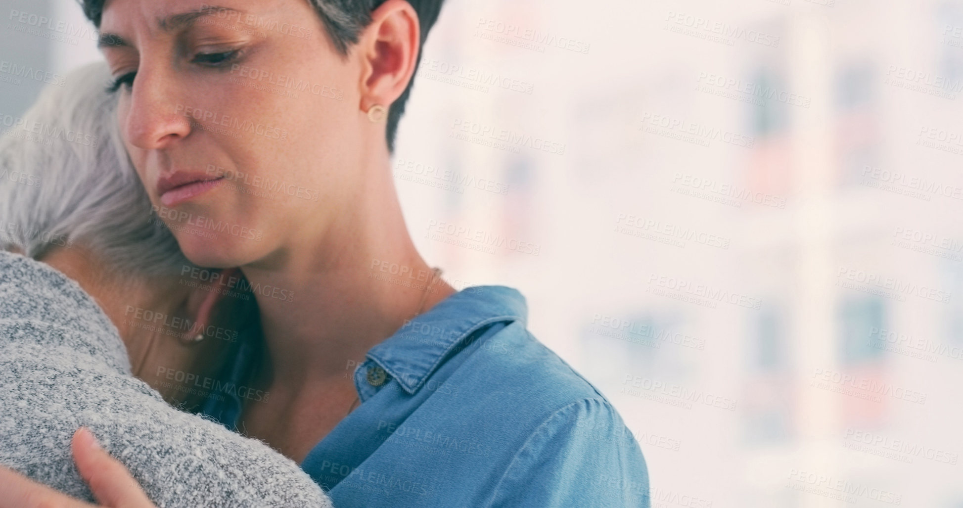 Buy stock photo Cropped shot of an attractive young woman hugging her senior mother closely while at home