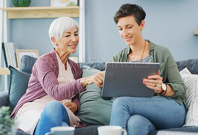 Buy stock photo Cropped shot of an attractive young woman sitting with her happy senior mother and using a tablet while at home