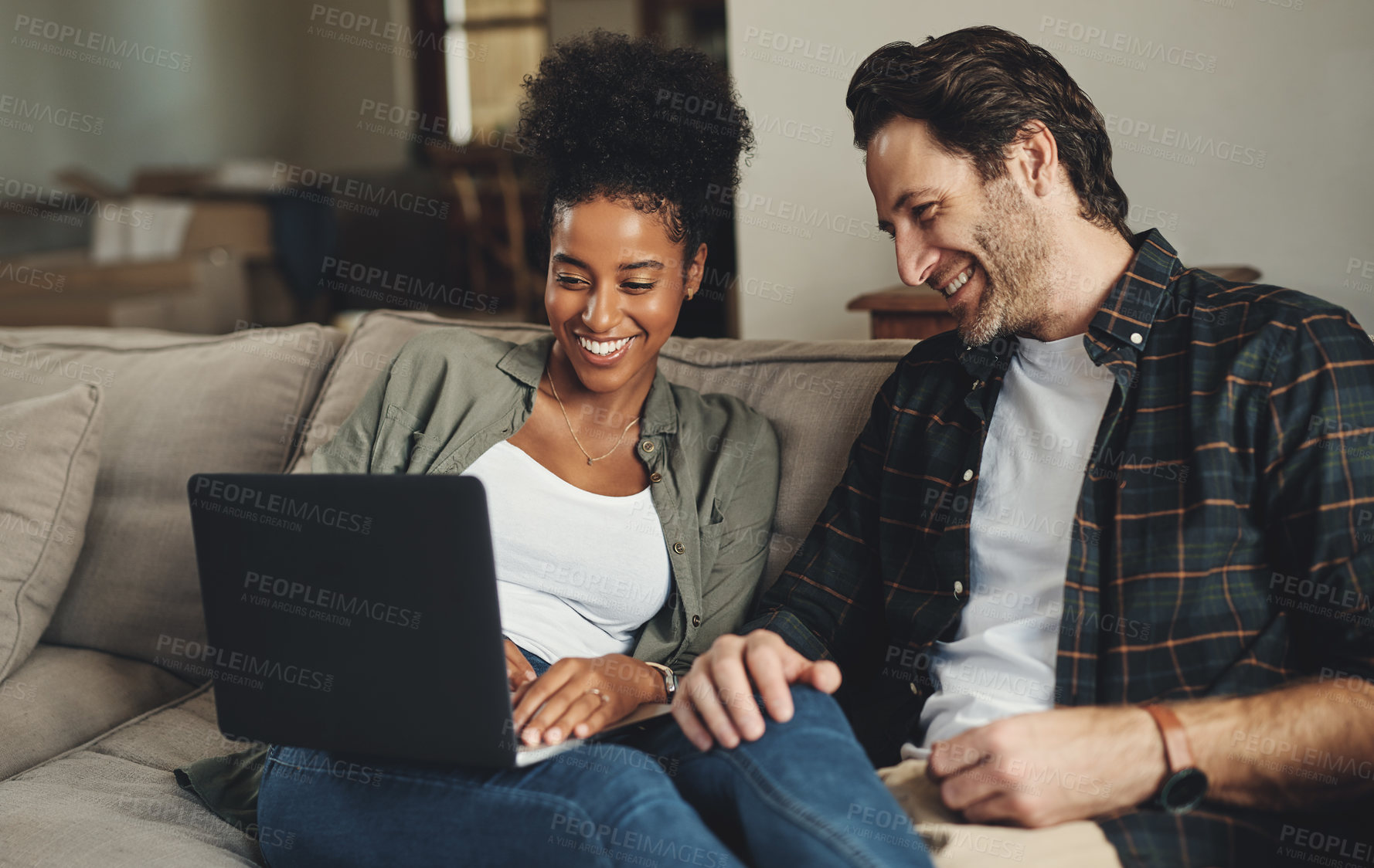 Buy stock photo Shot of a happy young couple using a laptop while relaxing on a couch in their living room at home