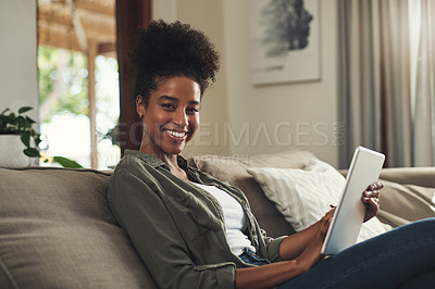 Buy stock photo Portrait of a beautiful young woman using a digital tablet while relaxing on her sofa at home