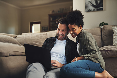 Buy stock photo Shot of a happy young couple using a laptop while relaxing on a couch in their living room at home