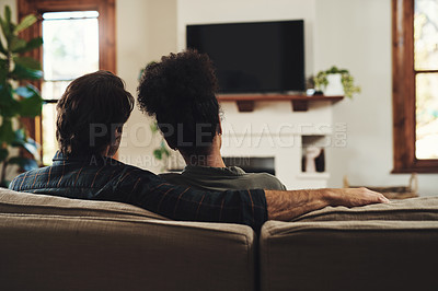 Buy stock photo Rearview shot of a young couple sitting on sofa and watching tv together at home