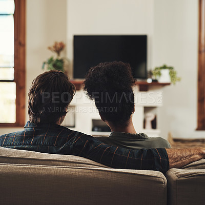 Buy stock photo Rearview shot of a young couple sitting on sofa and watching tv together at home