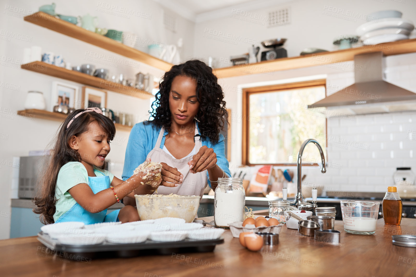 Buy stock photo Baking, help and mother with daughter in kitchen for bonding, food and learning. Cooking, love and cupcake with people and ingredients in family home for breakfast, teaching and happiness together