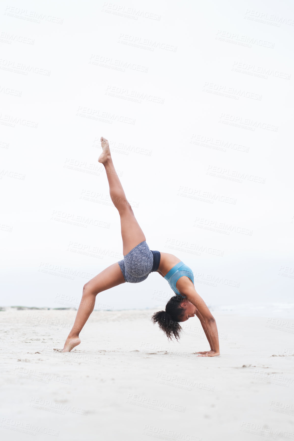 Buy stock photo Shot of a young woman doing a handstand at the beach