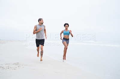 Buy stock photo Shot of a young couple running along the beach together