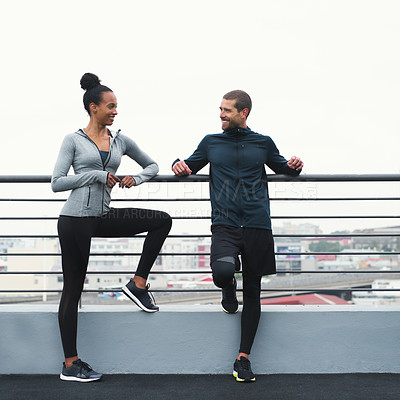 Buy stock photo Shot of a sporty young man and woman taking a break while exercising outdoors