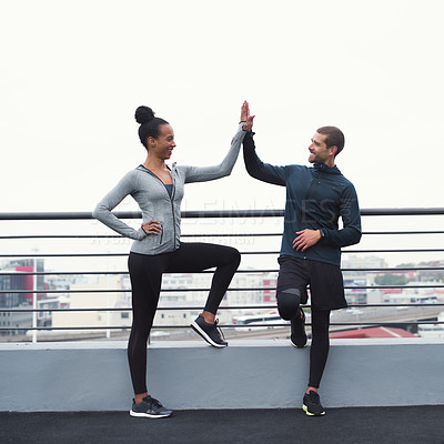 Buy stock photo Shot of a sporty young man and woman giving each other a high five while exercising outdoors