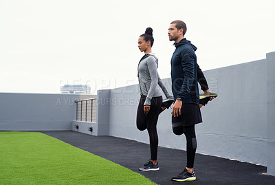 Buy stock photo Shot of a sporty young man and woman stretching while exercising together outdoors