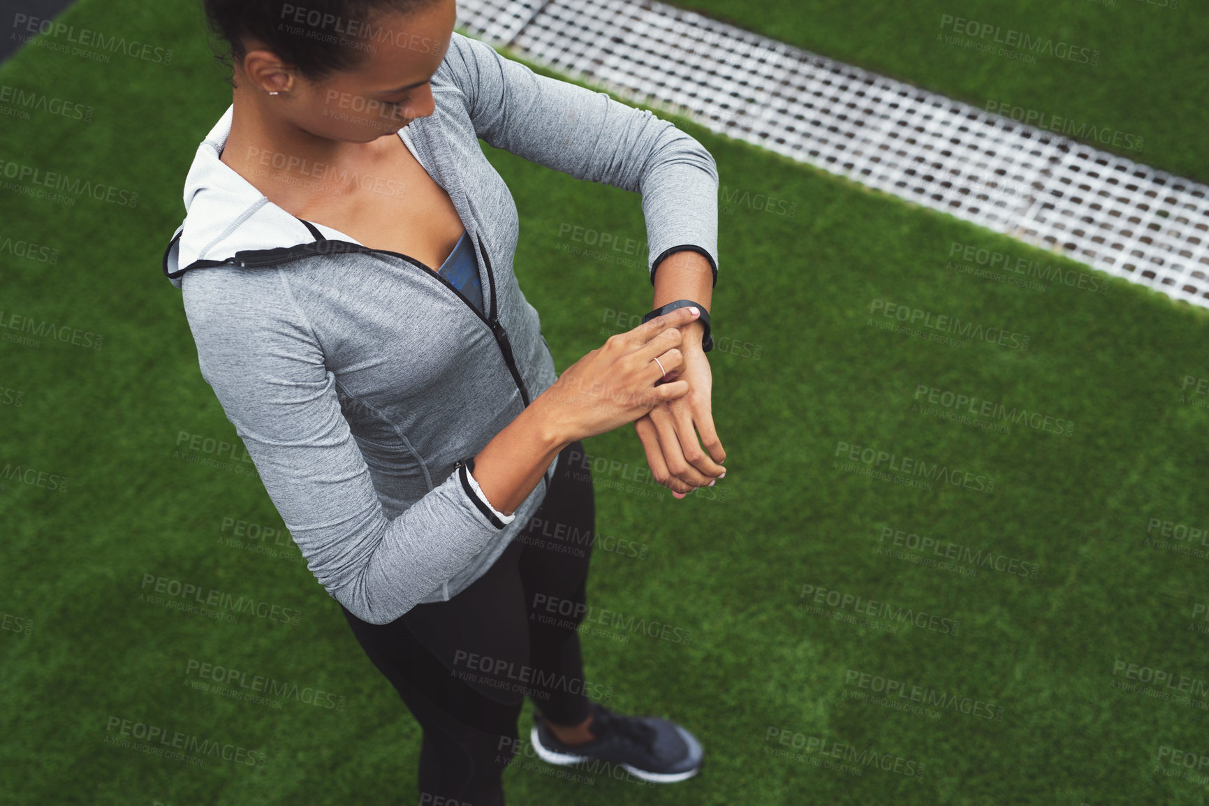 Buy stock photo High angle shot of a sporty young woman checking her watch while exercising outdoors