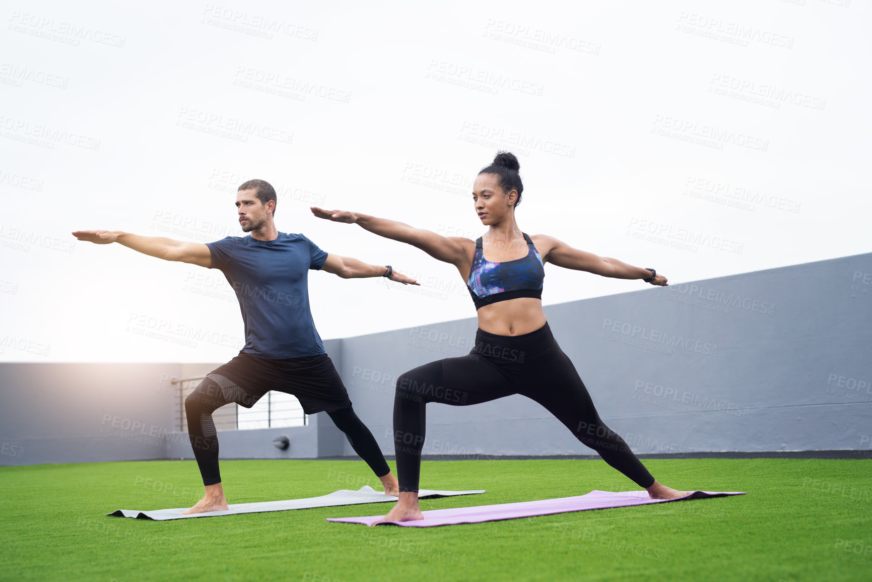 Buy stock photo Shot of a young man and woman practising yoga together outdoors