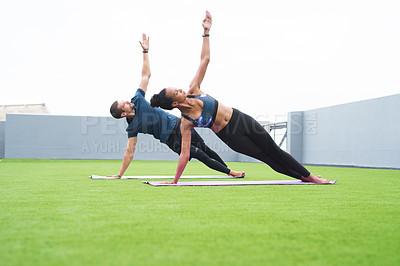 Buy stock photo Shot of a young man and woman practising yoga together outdoors