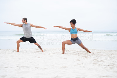 Buy stock photo Shot of a young man and woman practising yoga together at the beach