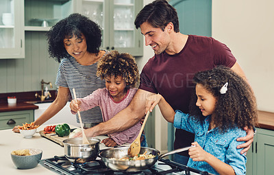 Buy stock photo Shot of a family of four cooking together in their kitchen at home