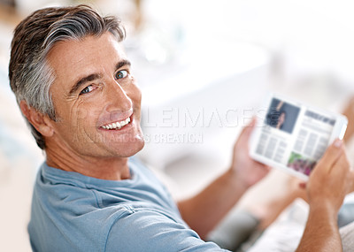 Buy stock photo Cropped portrait of a handsome mature man using a tablet while sitting on his living room sofa