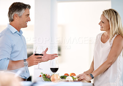 Buy stock photo Cropped shot of a mature couple enjoying wine and talking while making dinner together