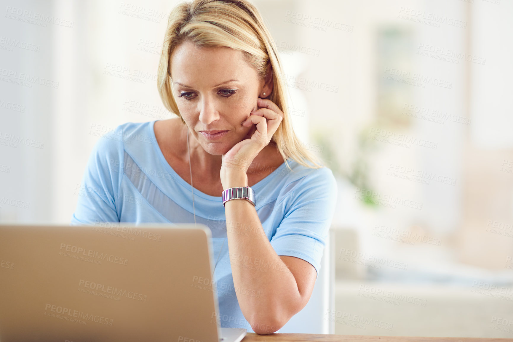 Buy stock photo Cropped shot of an attractive mature woman sitting and using a laptop while in her living room during the day
