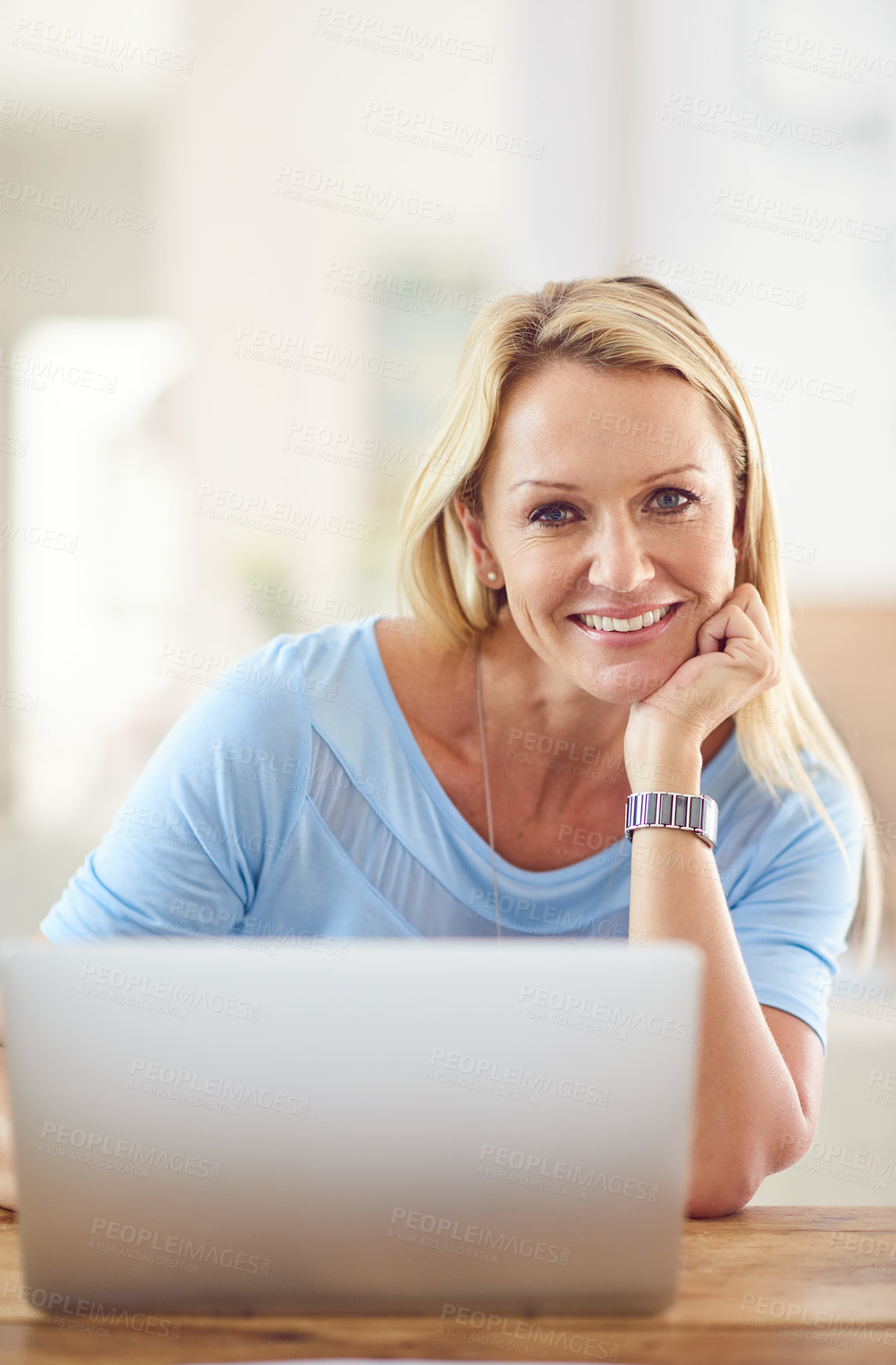 Buy stock photo Cropped portrait of an attractive mature woman sitting and using a laptop while in her living room during the day