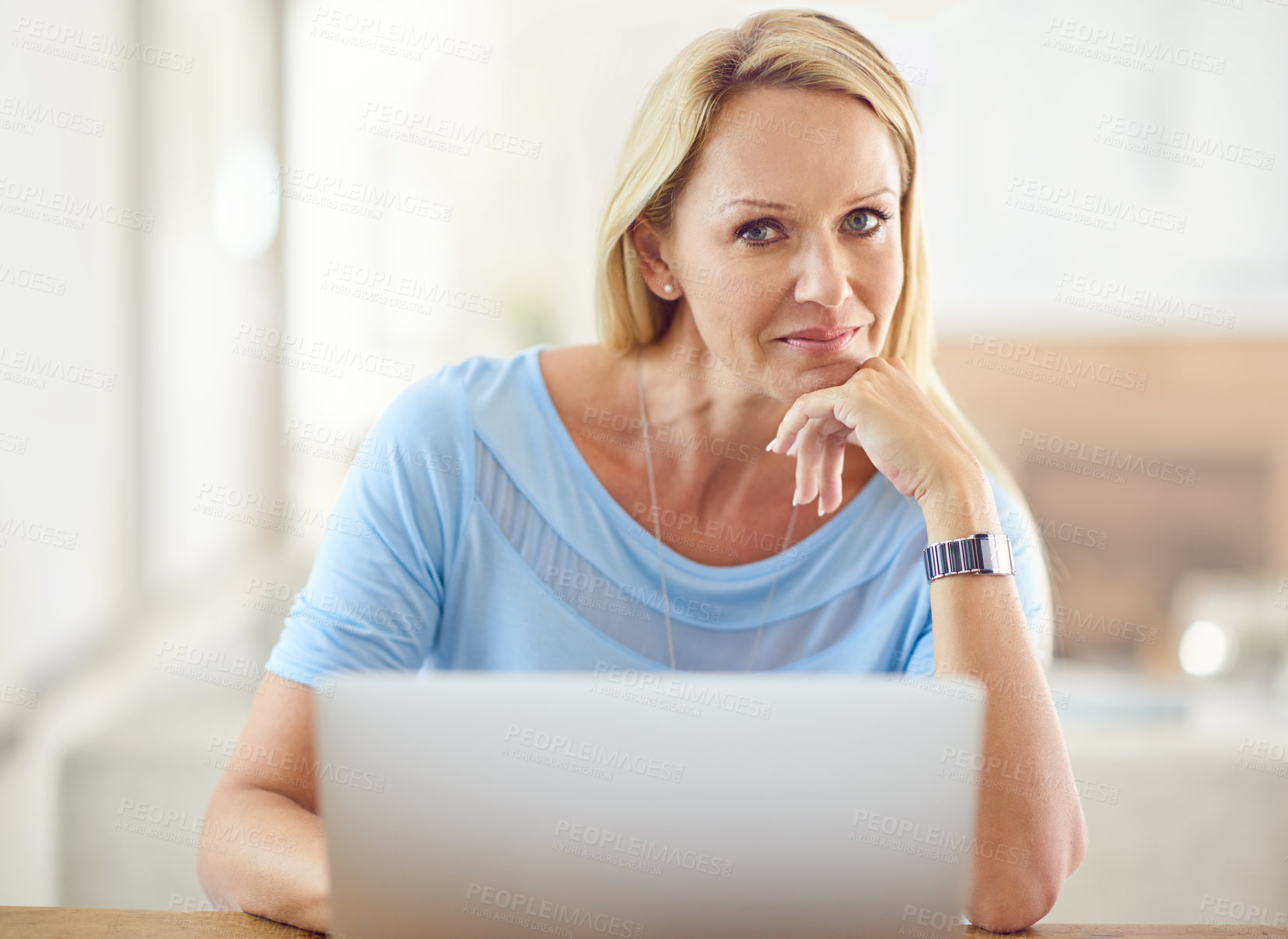 Buy stock photo Cropped portrait of an attractive mature woman sitting and using a laptop while in her living room during the day