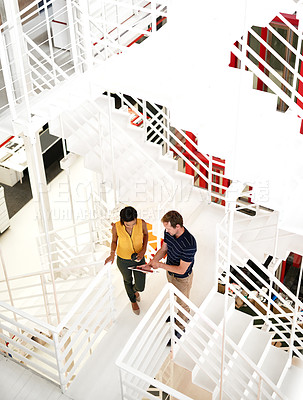 Buy stock photo High angle shot of two business colleagues standing together on a flight of stairs in the office