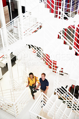 Buy stock photo High angle portrait of two business colleagues standing together on a flight of stairs in the office