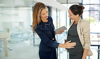 Buy stock photo Cropped shot of an attractive young businesswoman rubbing her attractive young coworker's pregnant stomach while standing in a modern office