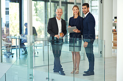 Buy stock photo Full length portrait of a group of young businesspeople standing together in a modern office and using a tablet