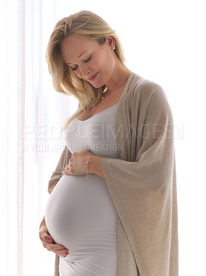 Buy stock photo Cropped shot of an attractive young pregnant woman holding her belly while standing in her home