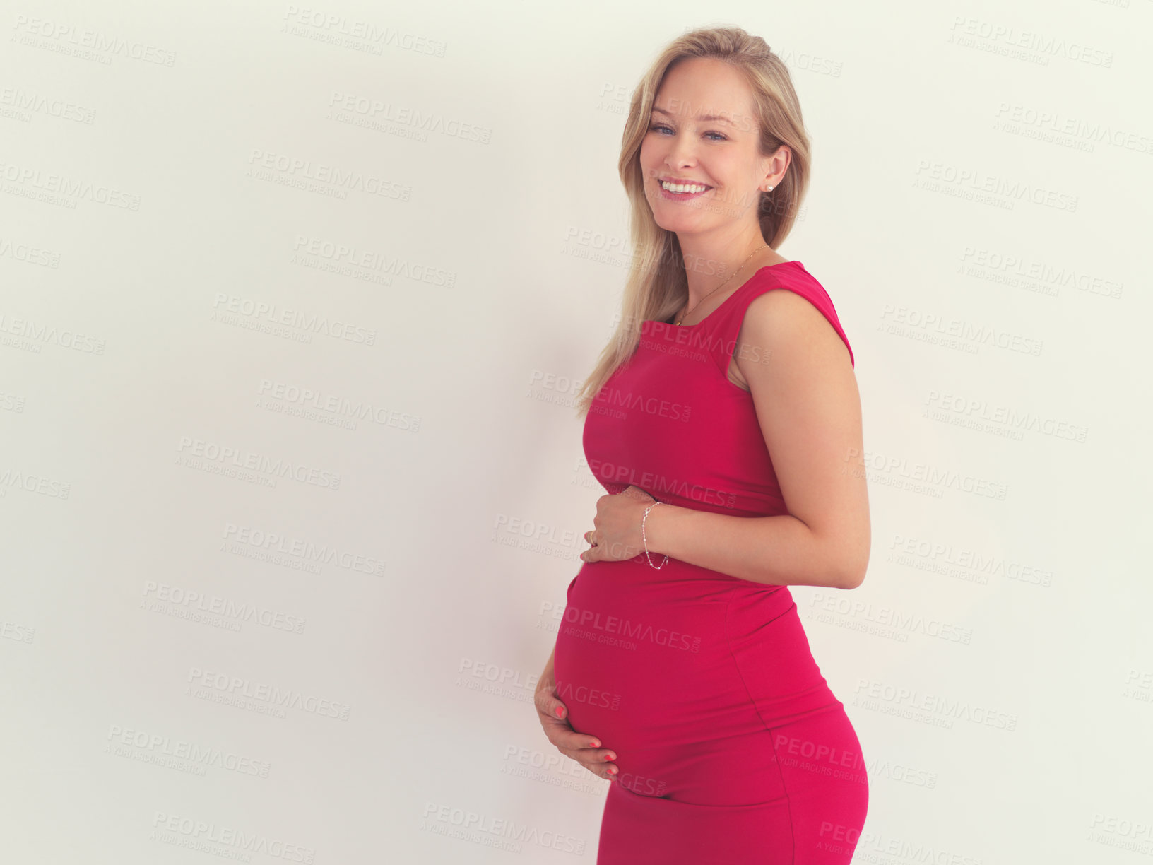 Buy stock photo Cropped portrait of an attractive young woman holding her belly while standing in her home