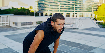 Buy stock photo Shot of a young man taking a break from his workout in the city