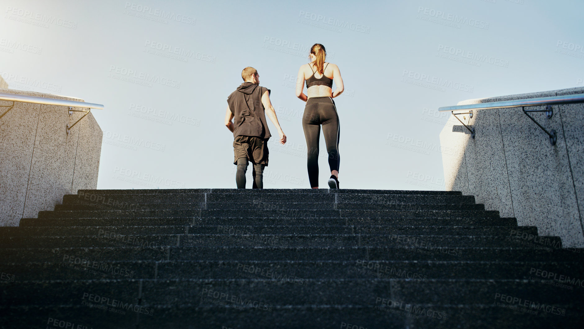 Buy stock photo Rearview shot of a young man and woman running up stairs together in the city