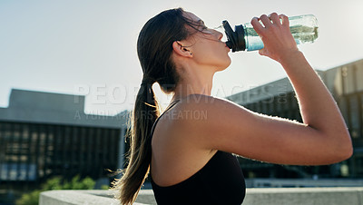 Buy stock photo Shot of a young woman drinking water during her workout in the city