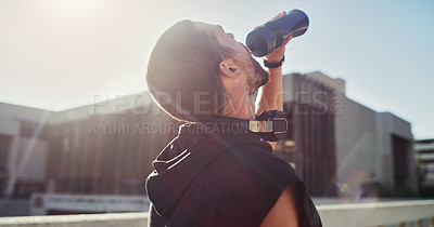 Buy stock photo Shot of a young man drinking water during his workout in the city