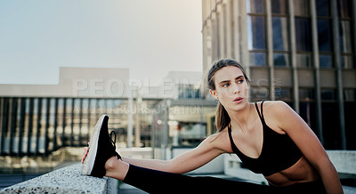Buy stock photo Shot of a young woman stretching during her workout in the city