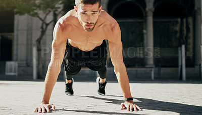 Buy stock photo Shot of a young man doing pushups during his workout in the city