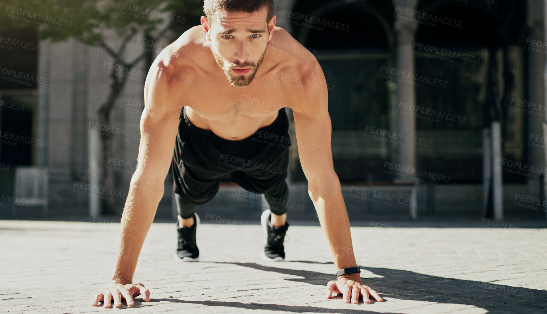 Buy stock photo Shot of a young man doing pushups during his workout in the city