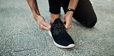 Buy stock photo Cropped shot of a man tying his shoelaces during a workout in the city