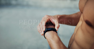Buy stock photo Cropped shot of an unrecognizable shirtless man looking at his watch while exercising in the city