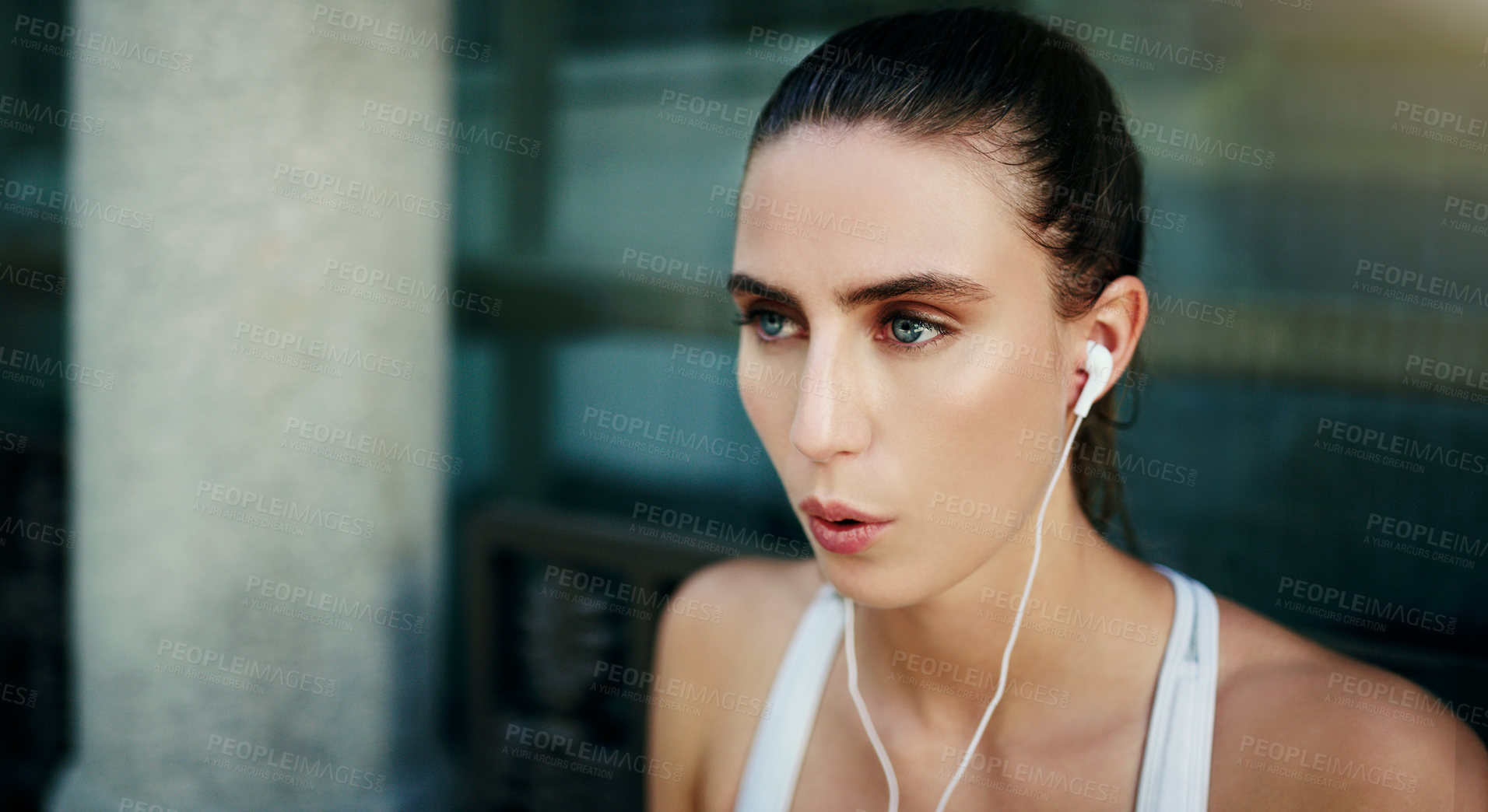 Buy stock photo Shot of a young woman listening to music during her workout in the city
