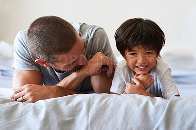 Buy stock photo Portrait of an adorable little boy lying on the bed with his father at home