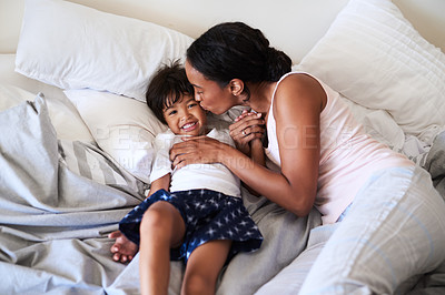 Buy stock photo Shot of a young mother kissing her little boy on the cheek in bed at home