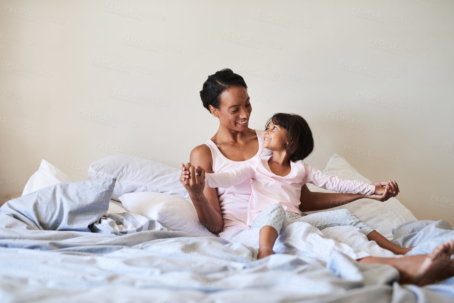 Buy stock photo Shot of a beautiful young mother bonding with her little girl in bed at home