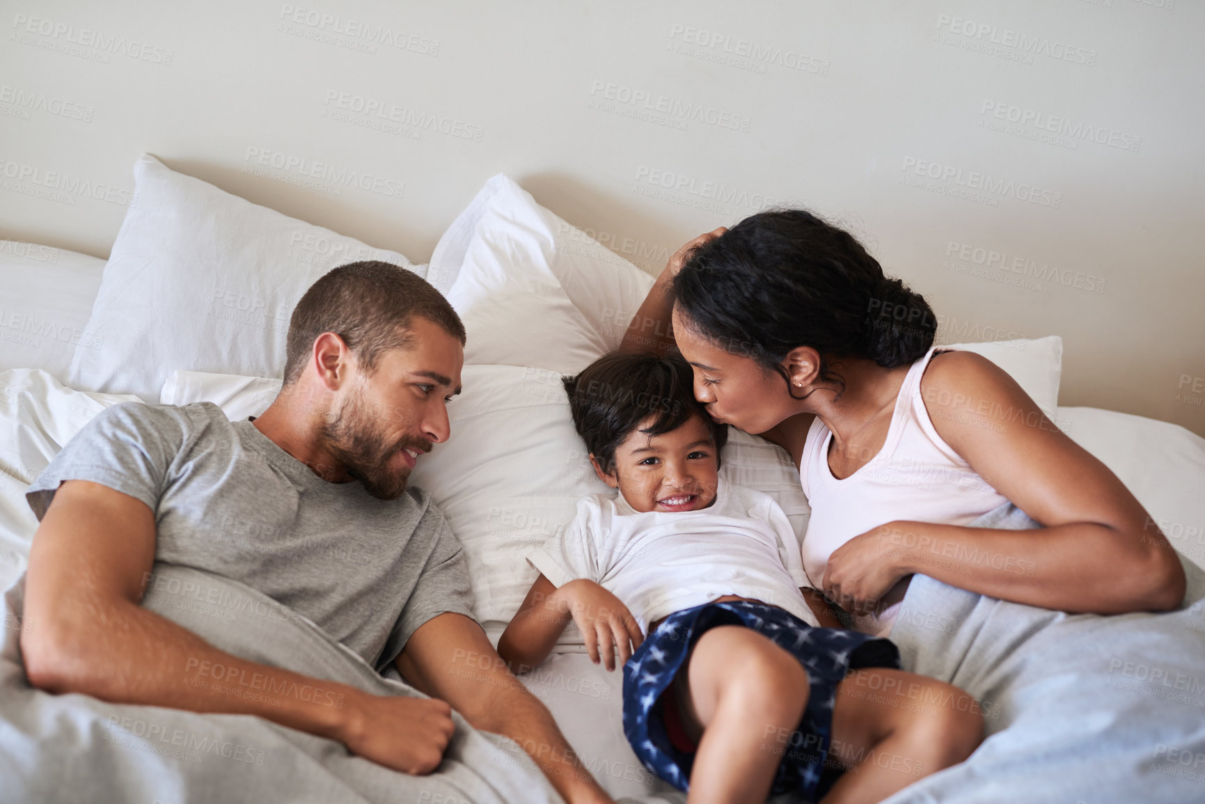 Buy stock photo Happy, morning and parents with child in bedroom for bonding, love and caring relationship. Family, childhood and mother, father and young boy together for calm, embrace and relax on bed in home