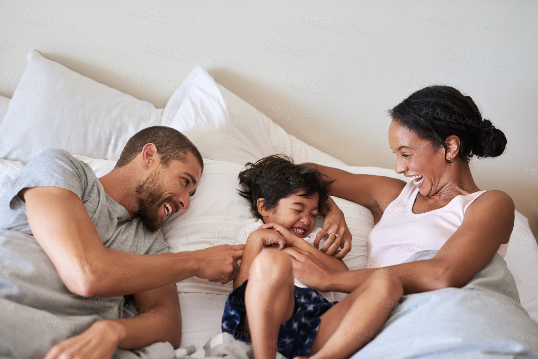 Buy stock photo Shot of a beautiful family of three spending time together in their bedroom at home